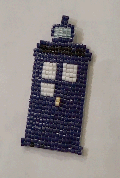 The TARDIS charm as a gif with the lights on and the lights turned off to show the glow-in-the-dark beads