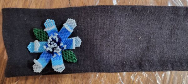 Beaded flower in shades of blue and green leaves on a black headband